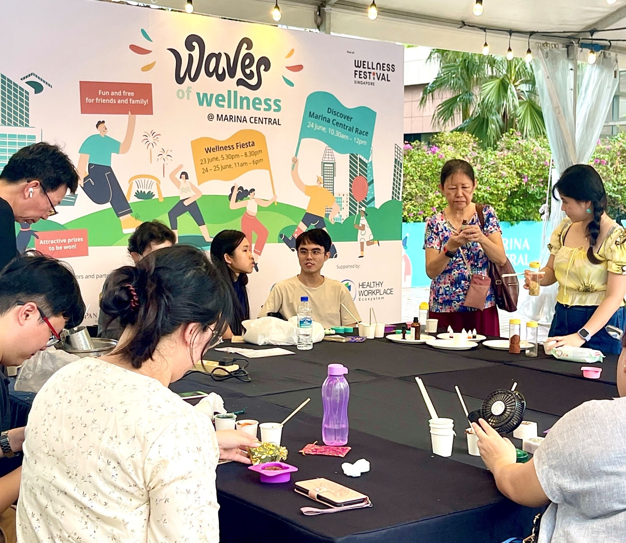 People gathered at a "Wellness Festival" event, participating in a crafting activity at a table.